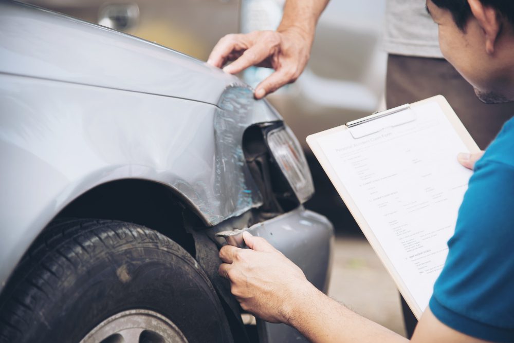 Two drivers inspecting vehicle damage to determine fault after an Illinois crash